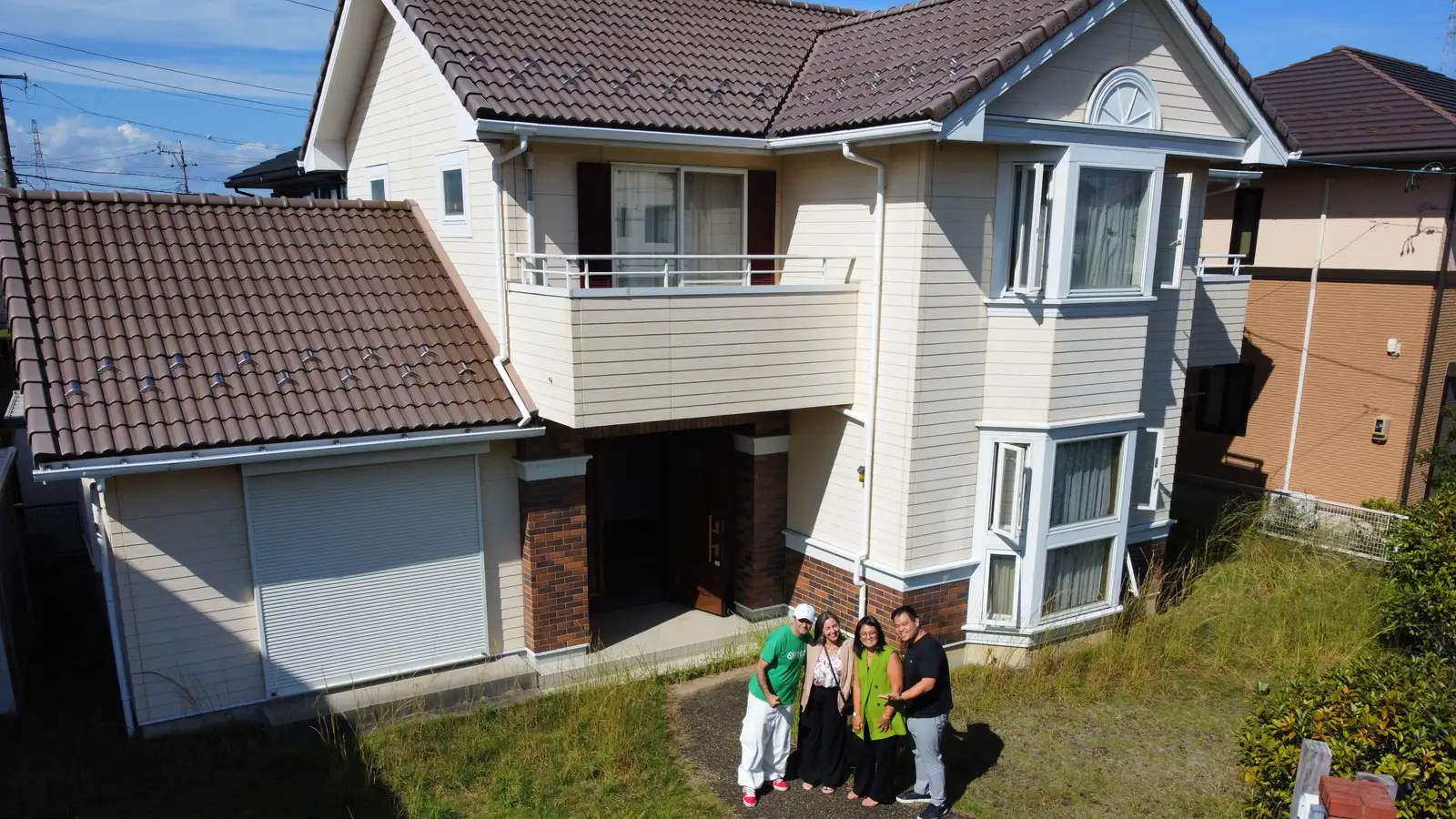 Família em frente à casa de dois andares que acabou de receber, vista de cima